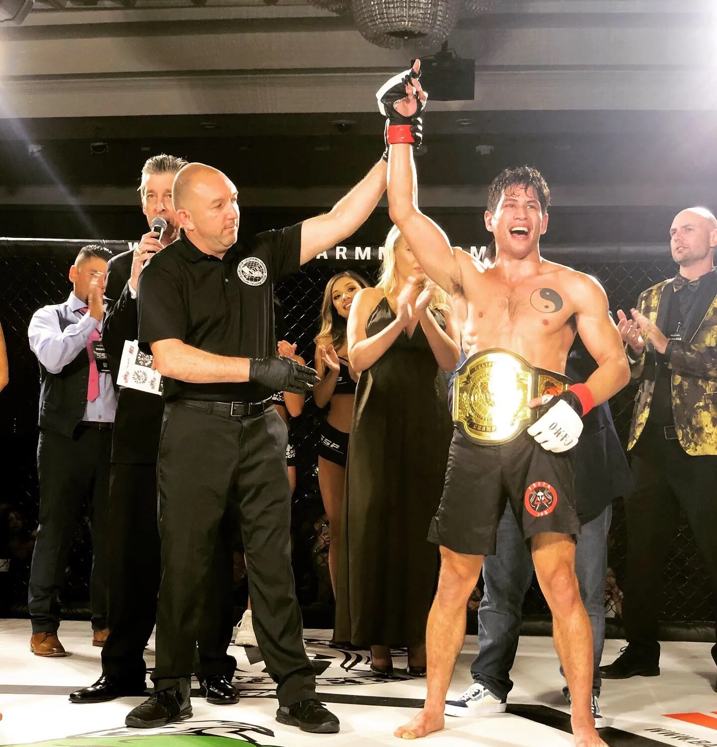 Johnny Faris having his hand raised in the cage, championship belt around his waist