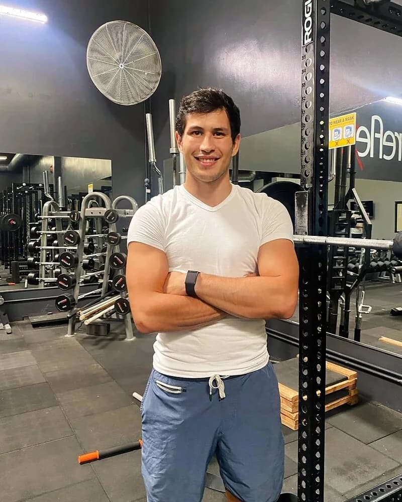 Johnny Faris, ChampLife personal trainer, standing at a power rack in the gym where he trains clients